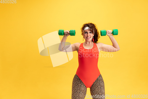 Image of Young caucasian plus size female model\'s training on yellow background