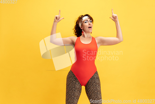 Image of Young caucasian plus size female model\'s training on yellow background