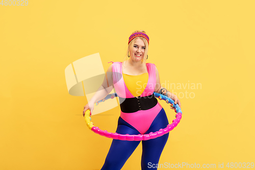 Image of Young caucasian plus size female model\'s training on yellow background