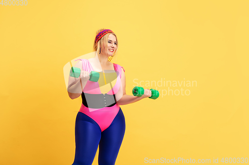 Image of Young caucasian plus size female model\'s training on yellow background