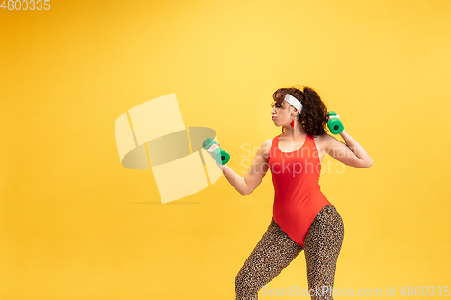 Image of Young caucasian plus size female model\'s training on yellow background