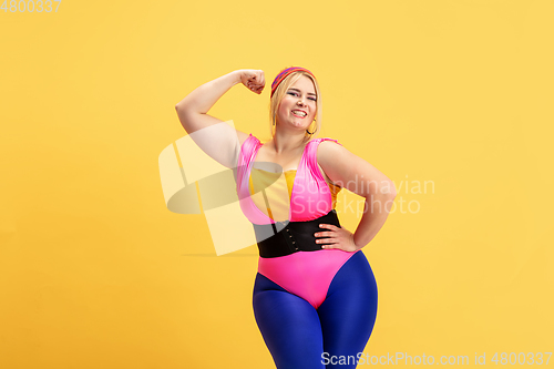 Image of Young caucasian plus size female model\'s training on yellow background