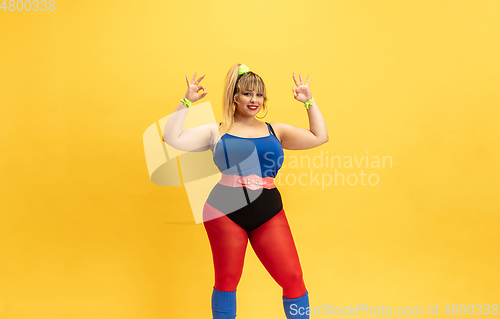Image of Young caucasian plus size female model\'s training on yellow background