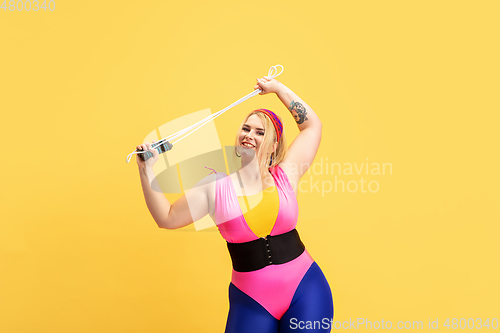 Image of Young caucasian plus size female model\'s training on yellow background