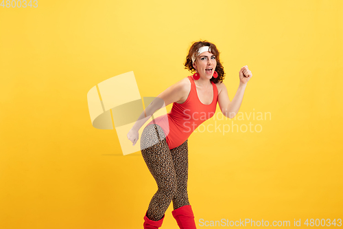 Image of Young caucasian plus size female model\'s training on yellow background