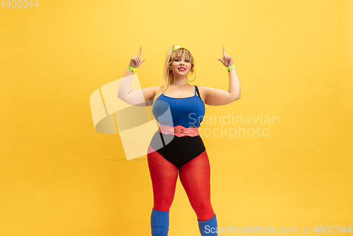 Image of Young caucasian plus size female model\'s training on yellow background