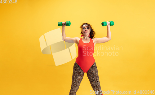 Image of Young caucasian plus size female model\'s training on yellow background