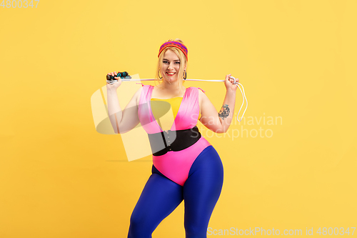 Image of Young caucasian plus size female model\'s training on yellow background