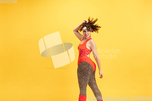 Image of Young caucasian plus size female model\'s training on yellow background