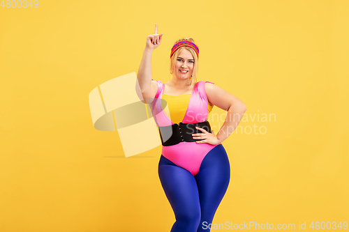 Image of Young caucasian plus size female model\'s training on yellow background