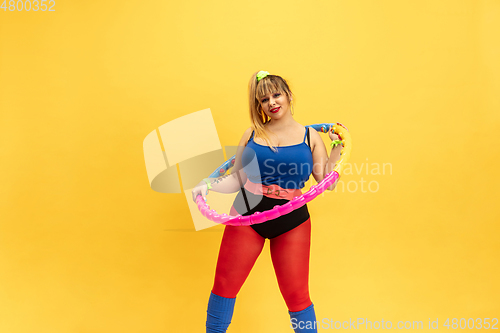 Image of Young caucasian plus size female model\'s training on yellow background