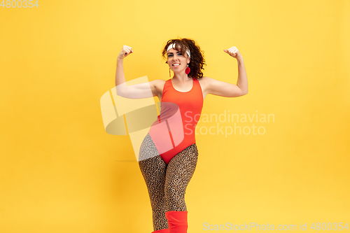 Image of Young caucasian plus size female model\'s training on yellow background