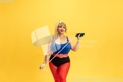 Image of Young caucasian plus size female model\'s training on yellow background