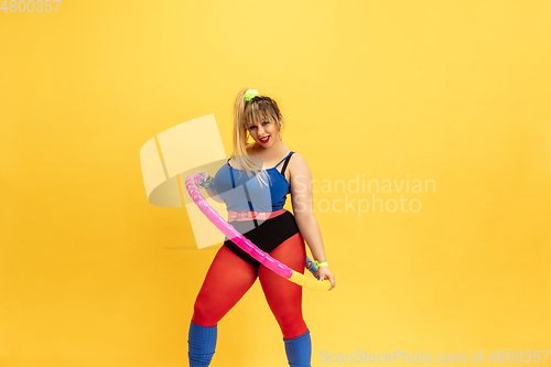Image of Young caucasian plus size female model\'s training on yellow background