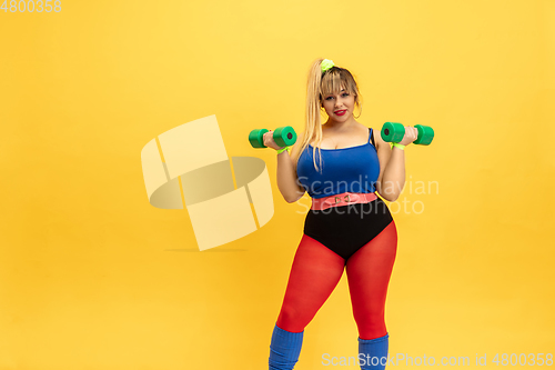 Image of Young caucasian plus size female model\'s training on yellow background