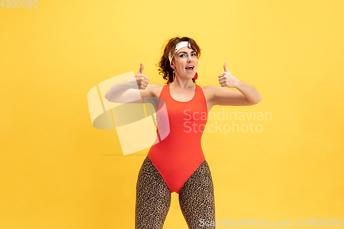 Image of Young caucasian plus size female model\'s training on yellow background