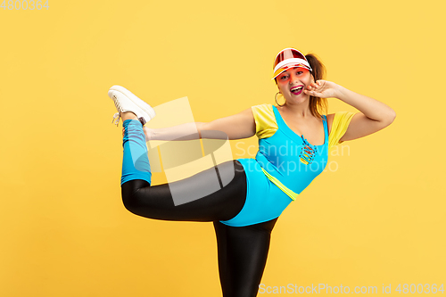 Image of Young caucasian plus size female model\'s training on yellow background