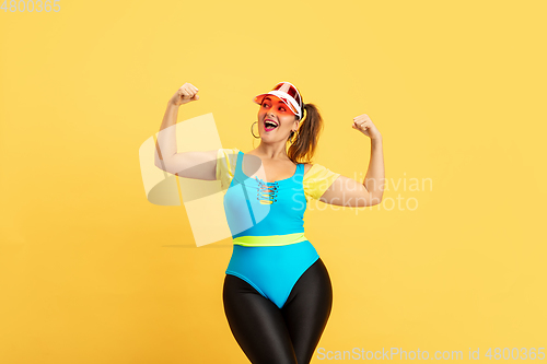Image of Young caucasian plus size female model\'s training on yellow background