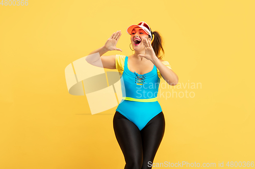 Image of Young caucasian plus size female model\'s training on yellow background