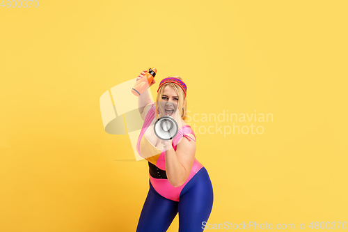 Image of Young caucasian plus size female model\'s training on yellow background