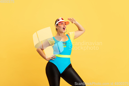 Image of Young caucasian plus size female model\'s training on yellow background