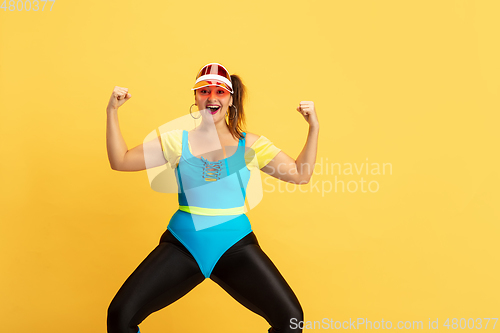 Image of Young caucasian plus size female model\'s training on yellow background