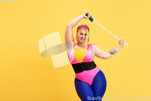 Image of Young caucasian plus size female model\'s training on yellow background