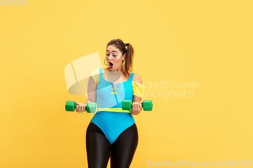 Image of Young caucasian plus size female model\'s training on yellow background