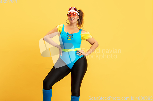 Image of Young caucasian plus size female model\'s training on yellow background