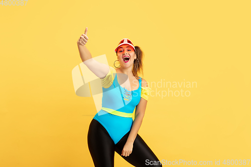 Image of Young caucasian plus size female model\'s training on yellow background