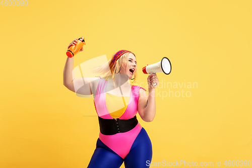 Image of Young caucasian plus size female model\'s training on yellow background