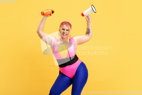 Image of Young caucasian plus size female model\'s training on yellow background