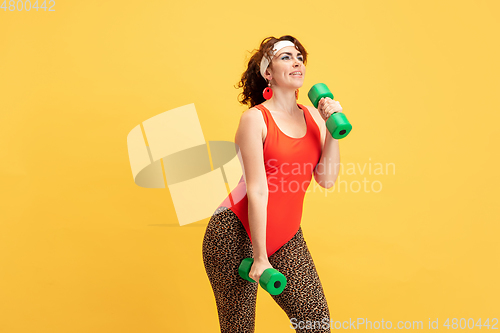 Image of Young caucasian plus size female model\'s training on yellow background