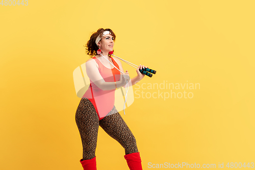 Image of Young caucasian plus size female model\'s training on yellow background