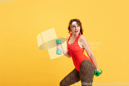 Image of Young caucasian plus size female model\'s training on yellow background