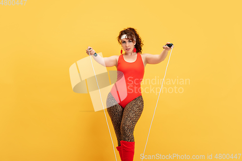 Image of Young caucasian plus size female model\'s training on yellow background