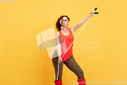 Image of Young caucasian plus size female model\'s training on yellow background