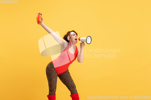 Image of Young caucasian plus size female model\'s training on yellow background