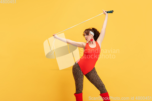 Image of Young caucasian plus size female model\'s training on yellow background