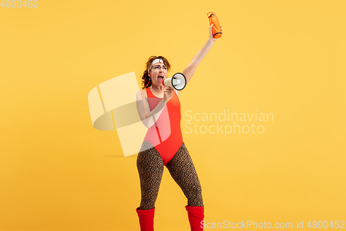 Image of Young caucasian plus size female model\'s training on yellow background