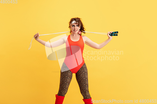 Image of Young caucasian plus size female model\'s training on yellow background