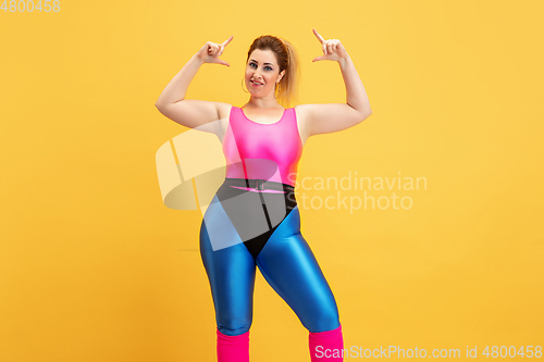 Image of Young caucasian plus size female model\'s training on yellow background