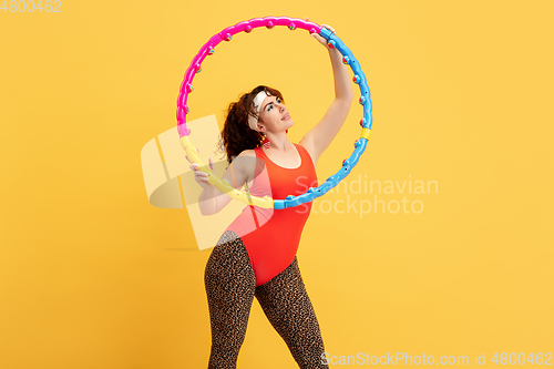 Image of Young caucasian plus size female model\'s training on yellow background