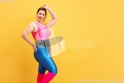 Image of Young caucasian plus size female model\'s training on yellow background