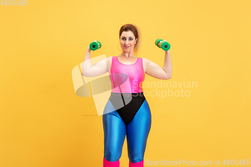 Image of Young caucasian plus size female model\'s training on yellow background