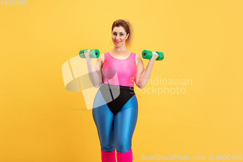 Image of Young caucasian plus size female model\'s training on yellow background