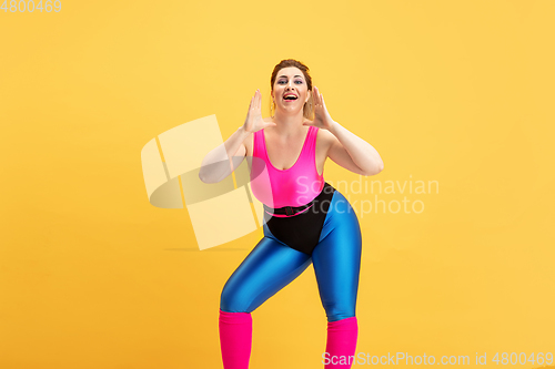 Image of Young caucasian plus size female model\'s training on yellow background