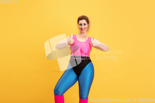 Image of Young caucasian plus size female model\'s training on yellow background
