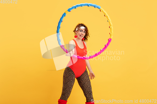Image of Young caucasian plus size female model\'s training on yellow background