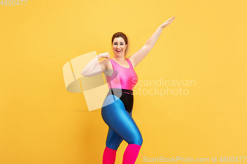 Image of Young caucasian plus size female model\'s training on yellow background